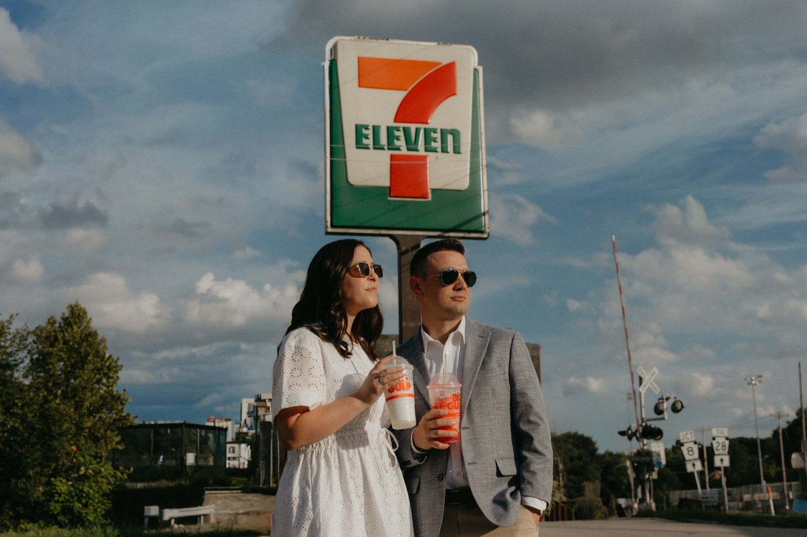 Andi and Dan under the 7-Eleven sign, drinks in hand